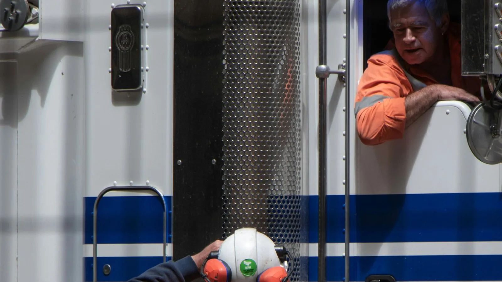Truck driver talking with a site worker in high-vis gear