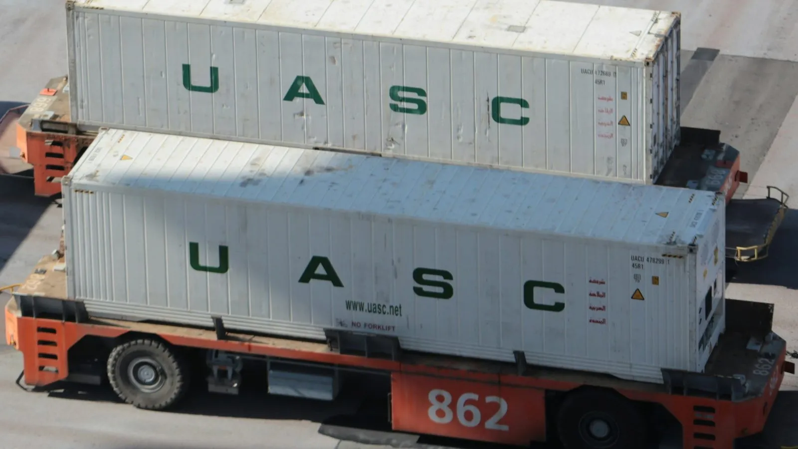 White refrigerated shipping containers being moved by terminal trucks at a container port
